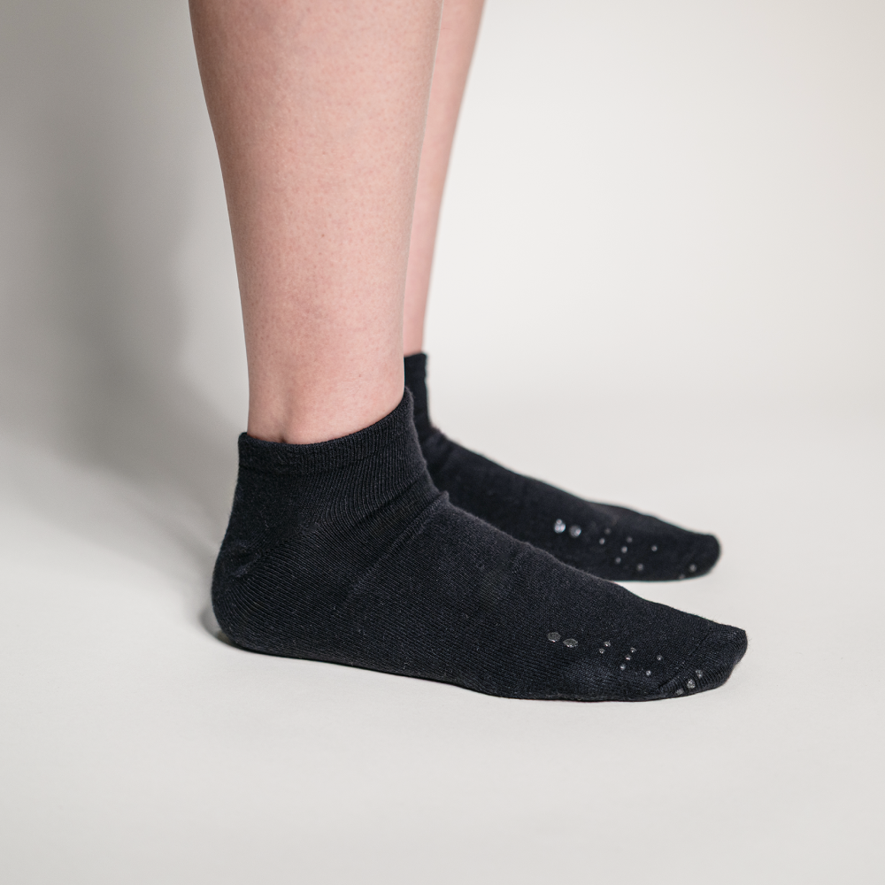 Side profile of a foot wearing a black ankle sock, showing how the tactile markers sit comfortably across the top of the toes for easy reach.