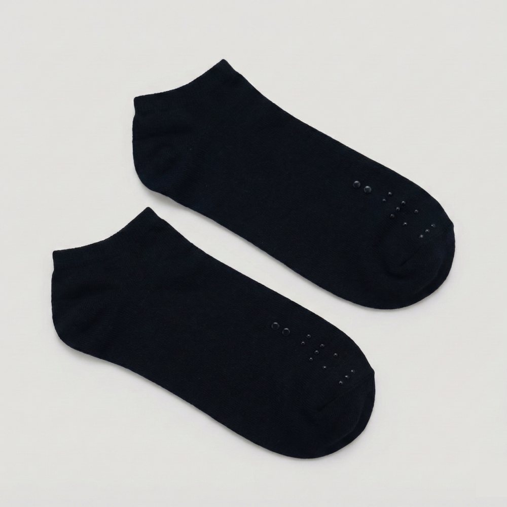 Flat lay of a pair of black ankle socks. The raised black-on-black tactile markers are positioned clearly on the toe area of each sock.