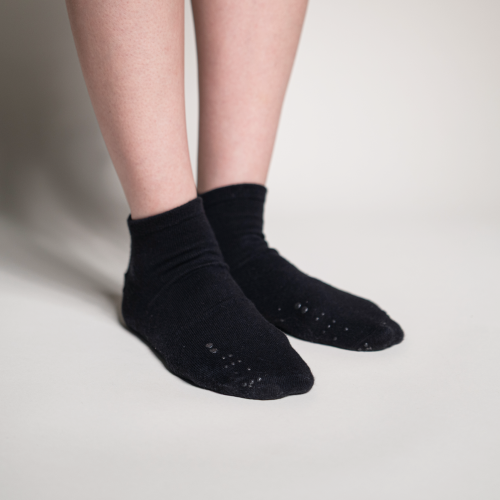 A pair of black Matchables ankle socks being worn, showing the subtle raised tactile markers located on the top of the toe area.