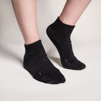 Perspective view of a model wearing black ankle socks, demonstrating the discreet and integrated look of the tactile identification system.