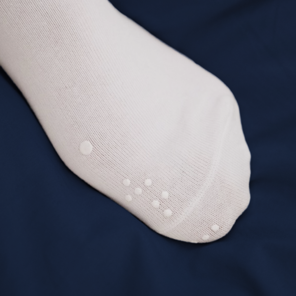 Close-up of the toe area on a white ankle sock, featuring raised, 3D-printed white tactile dots for touch-based color identification.
