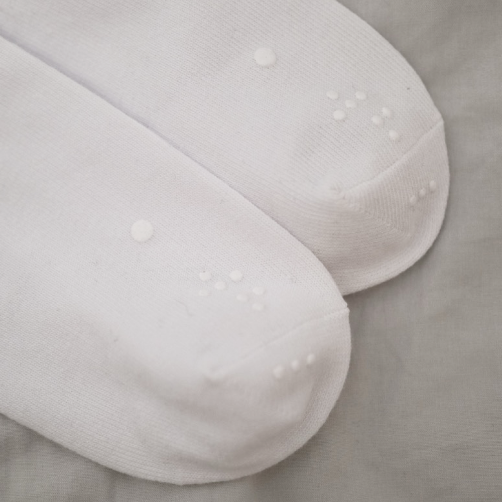 Detailed view of the toe sections of two white socks, showcasing the consistent pattern of the raised identification dots.